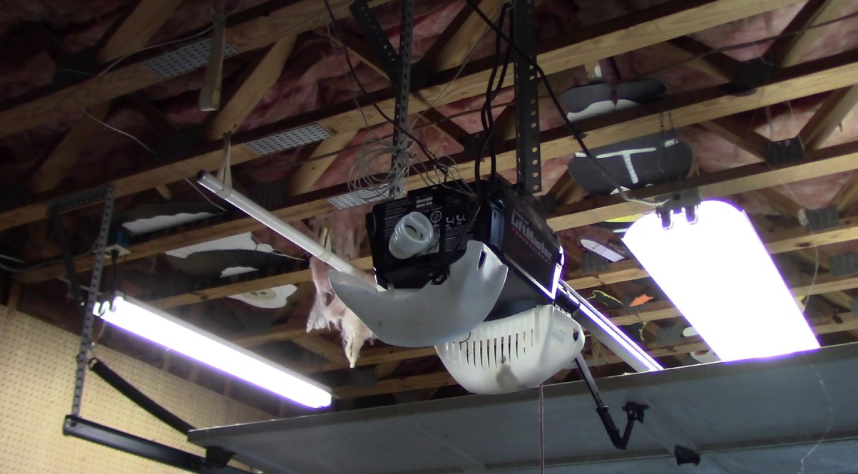 Alt Text: A technician from Orlando FL Garage Door Repair Services fixing a garage door opener mechanism, showcasing professional repair services in Orlando, Florida.